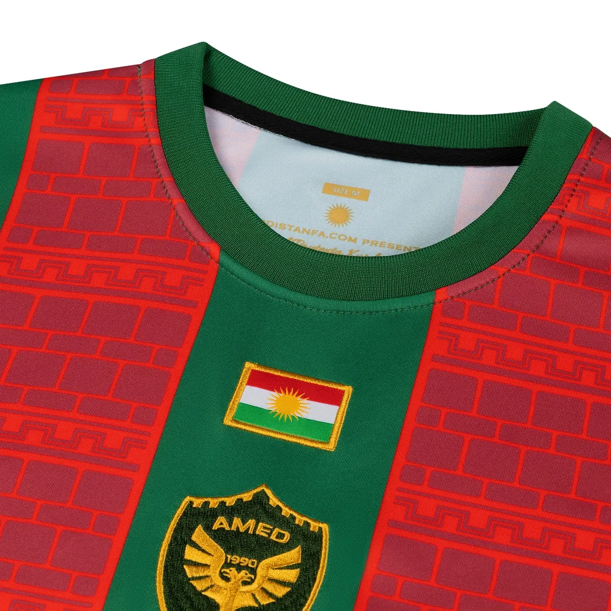 Close-up of the embroidered flag of Kurdistan and the golden AMED 1990 eagle crest on the home shirt
